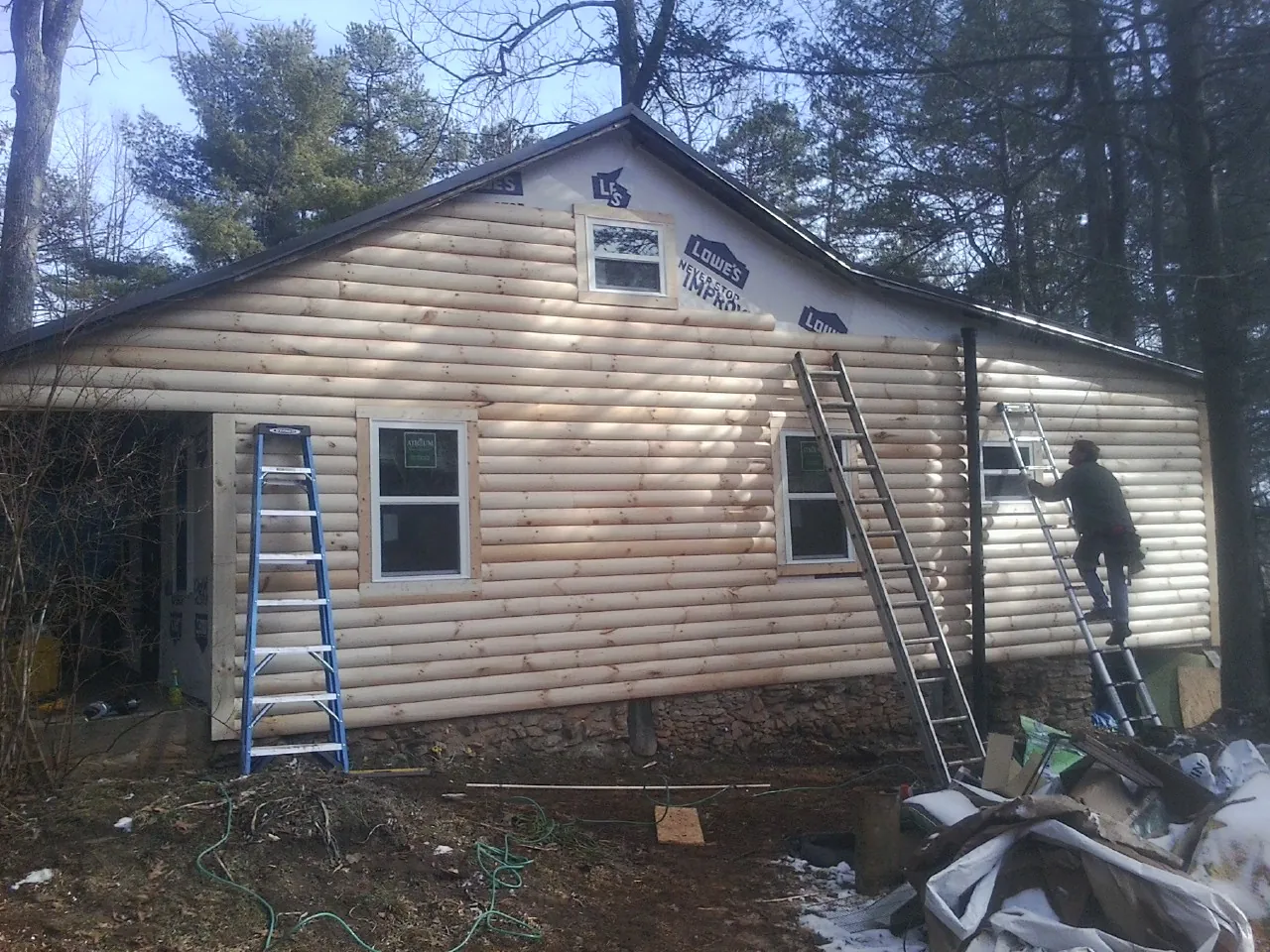 Ladders set against fresh log siding during an exterior remodel in Maxbass