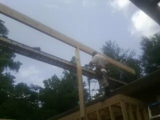 Carpenter setting a ridge beam over a new addition frame — Ice Dam Removal by Roofing Brothers in Maxbass
