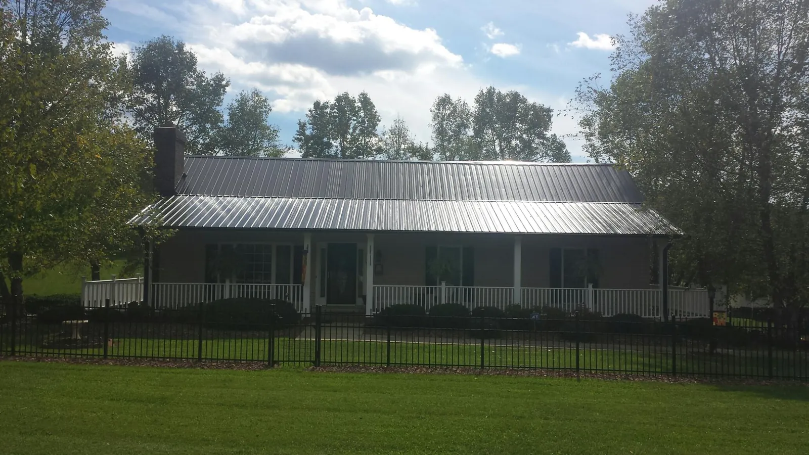 Gray metal roof on a brick ranch with a full width front porch — Gutter Guard Installation work by our crew in Maxbass