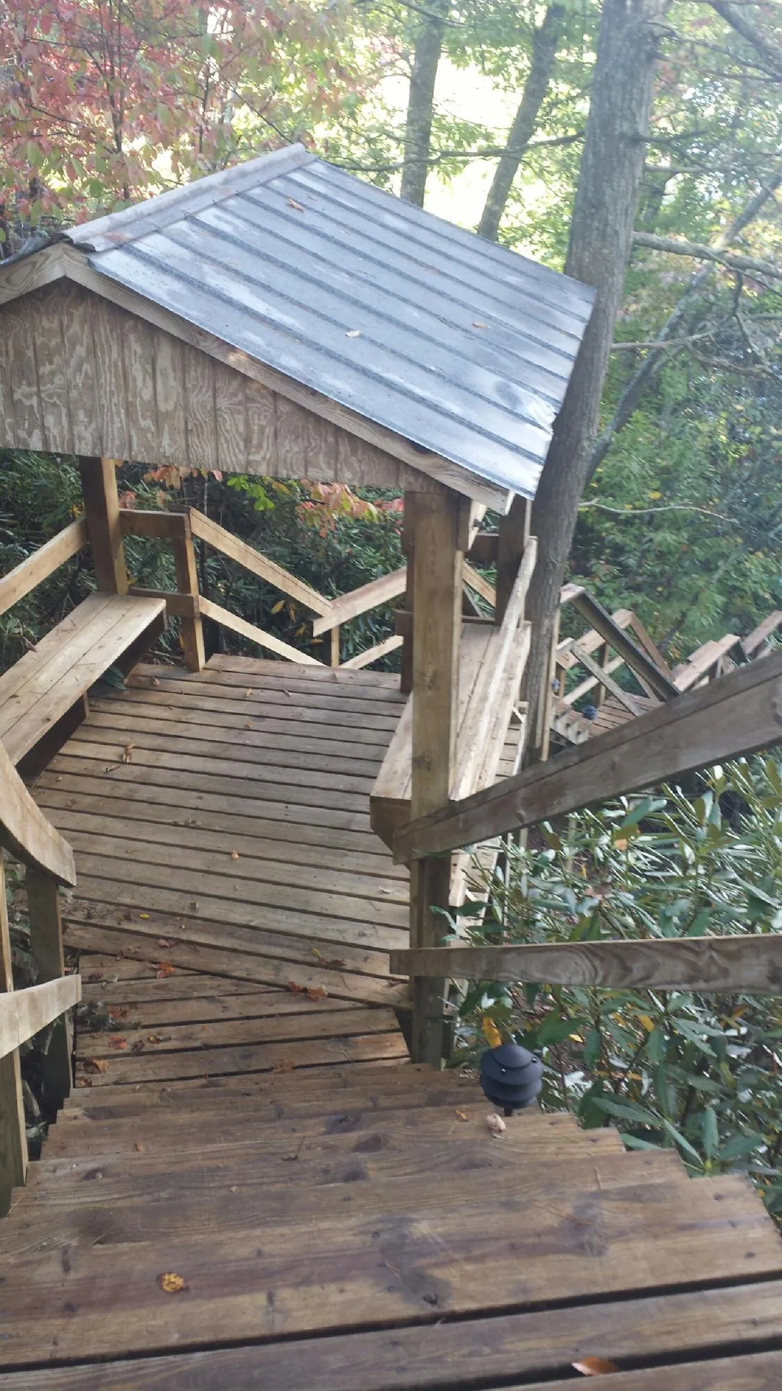 Metal roofed shelter over wooden steps on a wooded walkway — Skylight Repair & Installation work by our crew in Maxbass