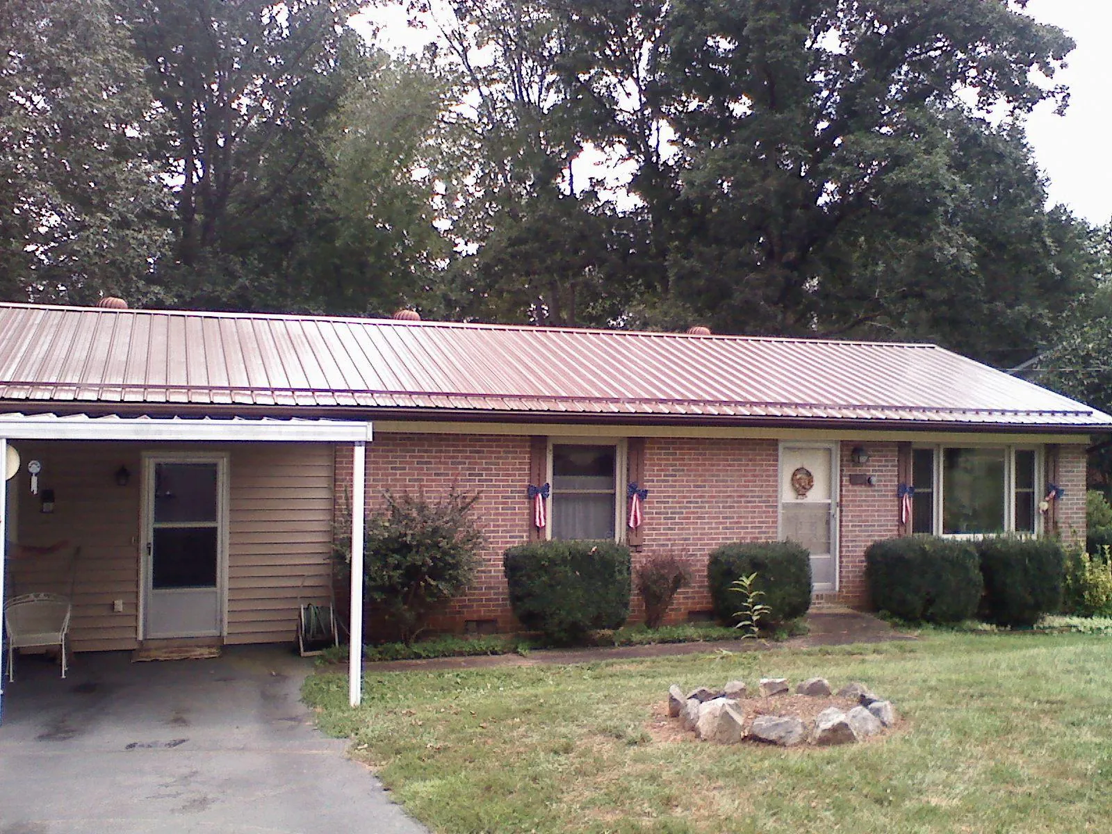 Bronze metal roof and carport on a brick ranch home — Roof Repair work by our crew in Maxbass